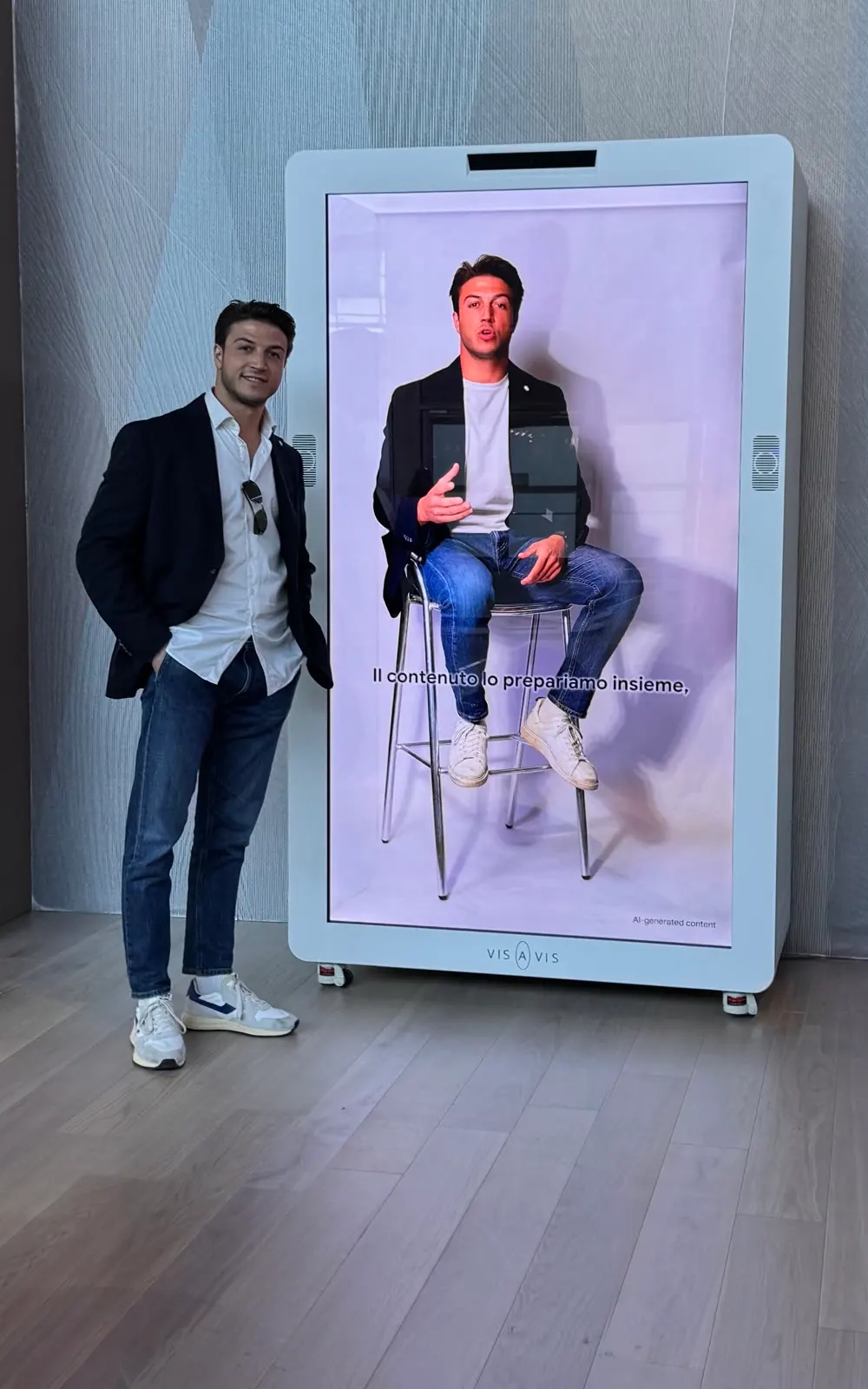 Federico Pizzinelli accanto al totem Vis a Vis che mostra il suo avatar AI